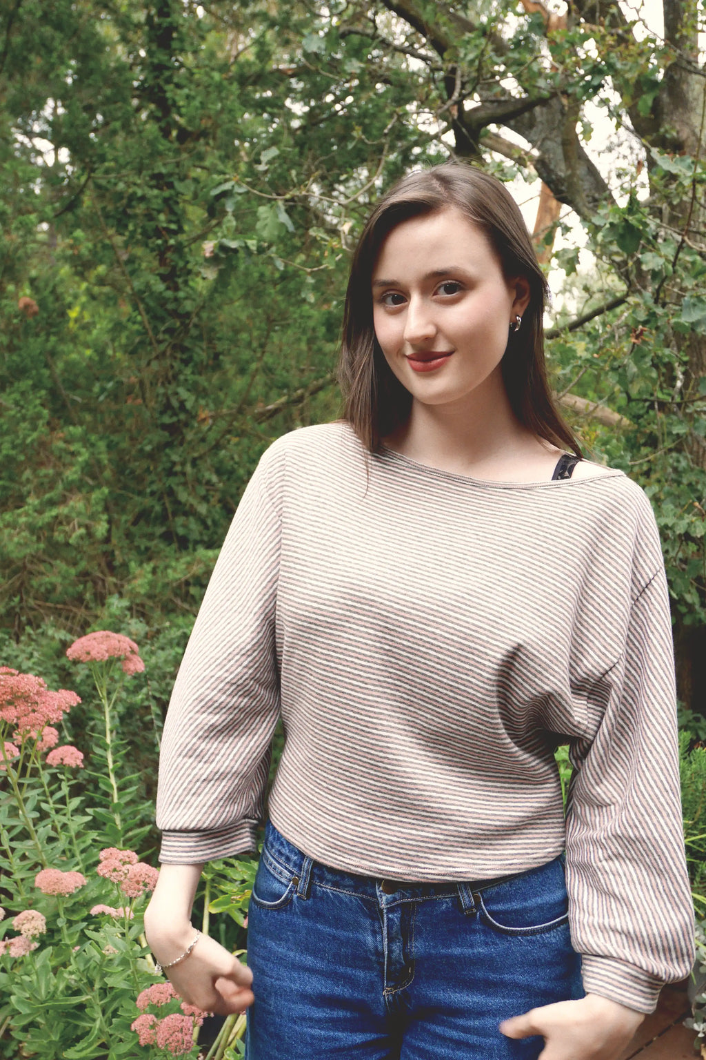 young woman wearing a pink striped oversized cotton boat neck pullover top, with long sleeves outside